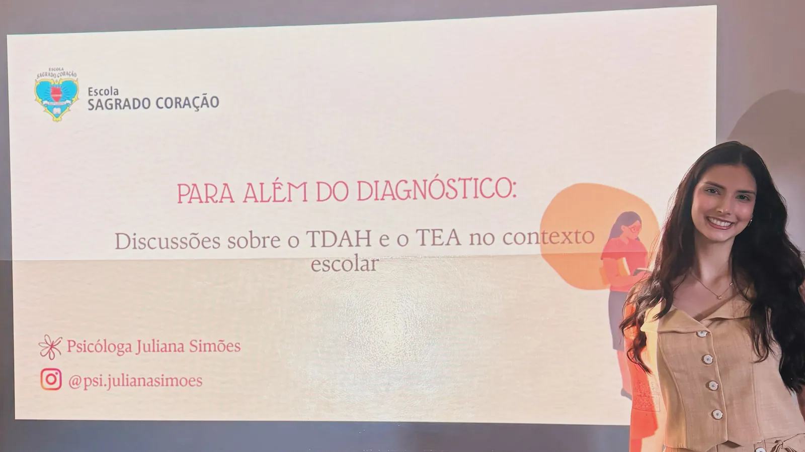 Juliana ao lado da projeção com o título da conversa, “Para além do diagnóstico: discussões sobre o TDAH e o TEA no contexto escolar”